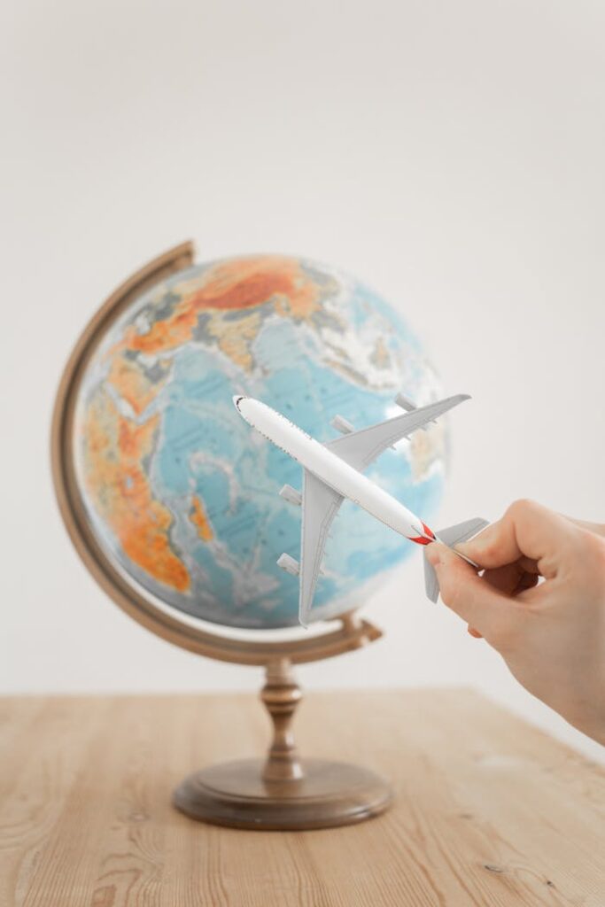 pexels photo 7412001 Close-up of a hand with a toy airplane in front of a globe, symbolizing travel and exploration.